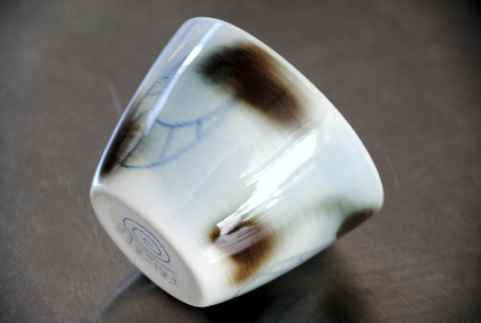 Handgemachte Porzellan-Tasse Super Cup abnorm Hengst von FRIZBEE CERAMICS. Die Detailaufnahme zeigt die schräge Seitenansicht des Bechers mit rauchigen, dunkelbraunen Airbrush-Akzenten und feinen blauen Linienzeichnungen auf hellem Grund sowie die wellige, organische Form.